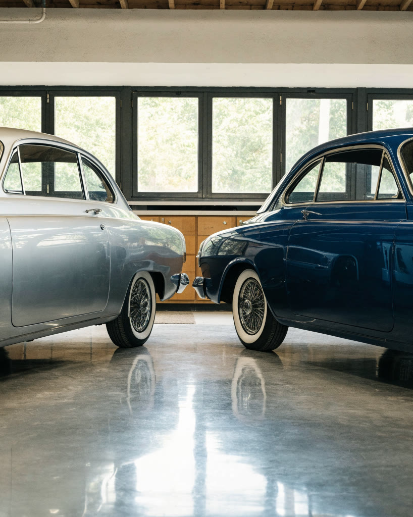 Dos autos clásicos restaurados, uno plata y otro azul, dentro del taller