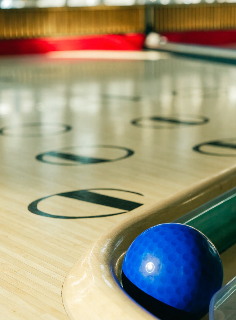 Madera clara de la pista con flechas guía y una bola azul en el regreso