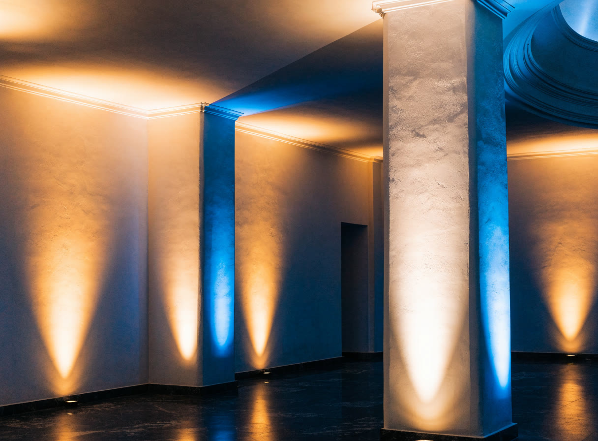 Muro de salón iluminado desde el piso con luz ámbar y azul