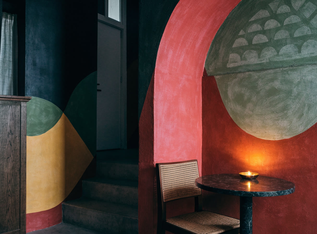 Rincón de restaurante con arcos pintados en terracota, rosa y olivo