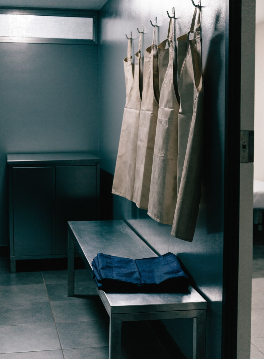 Vestidor con banca, bata doblada y mandiles de plomo colgados