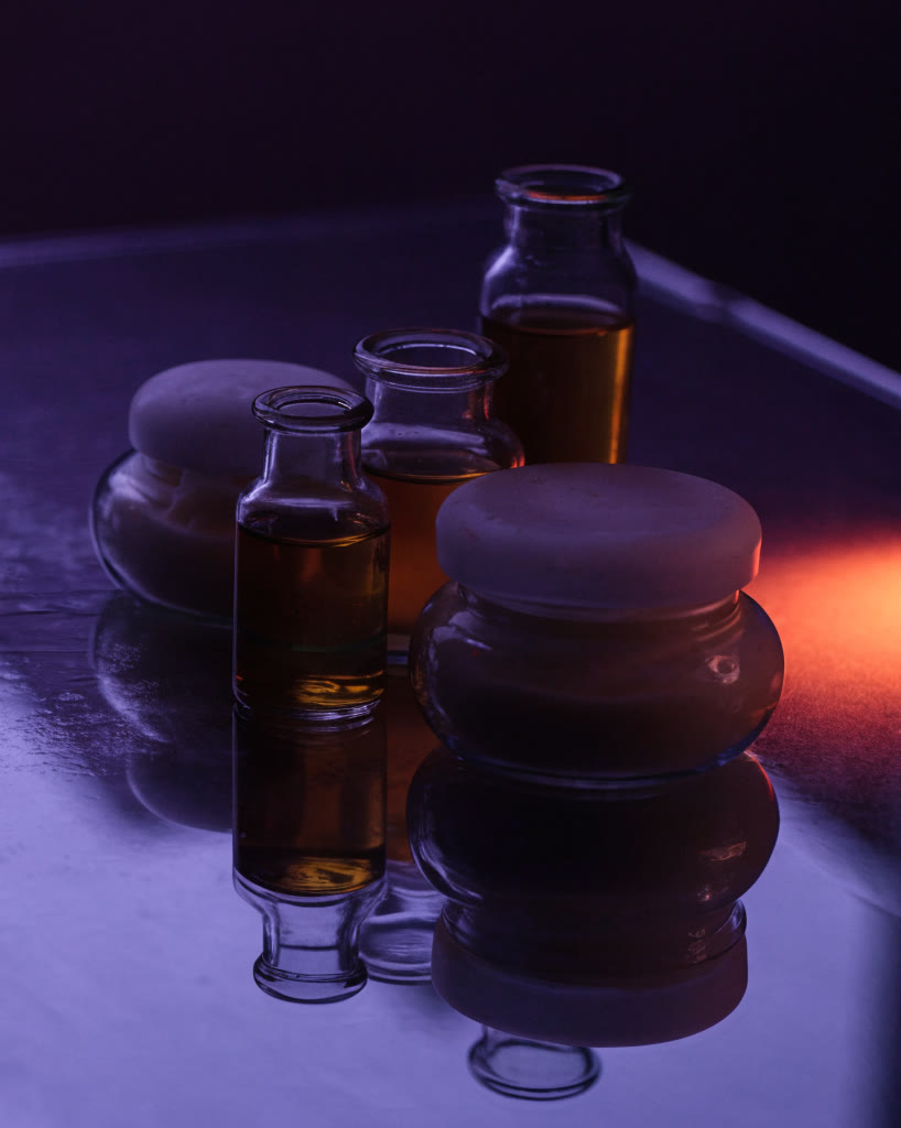 Frascos de vidrio y tarros sobre un escenario violeta con luz coral