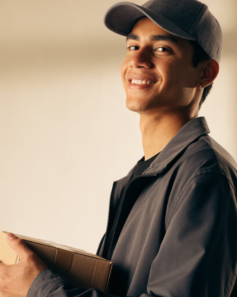 Mensajero sonriente con un paquete sellado en la mano